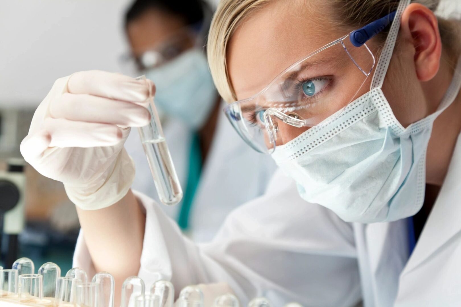 A woman in white lab coat holding a tube.